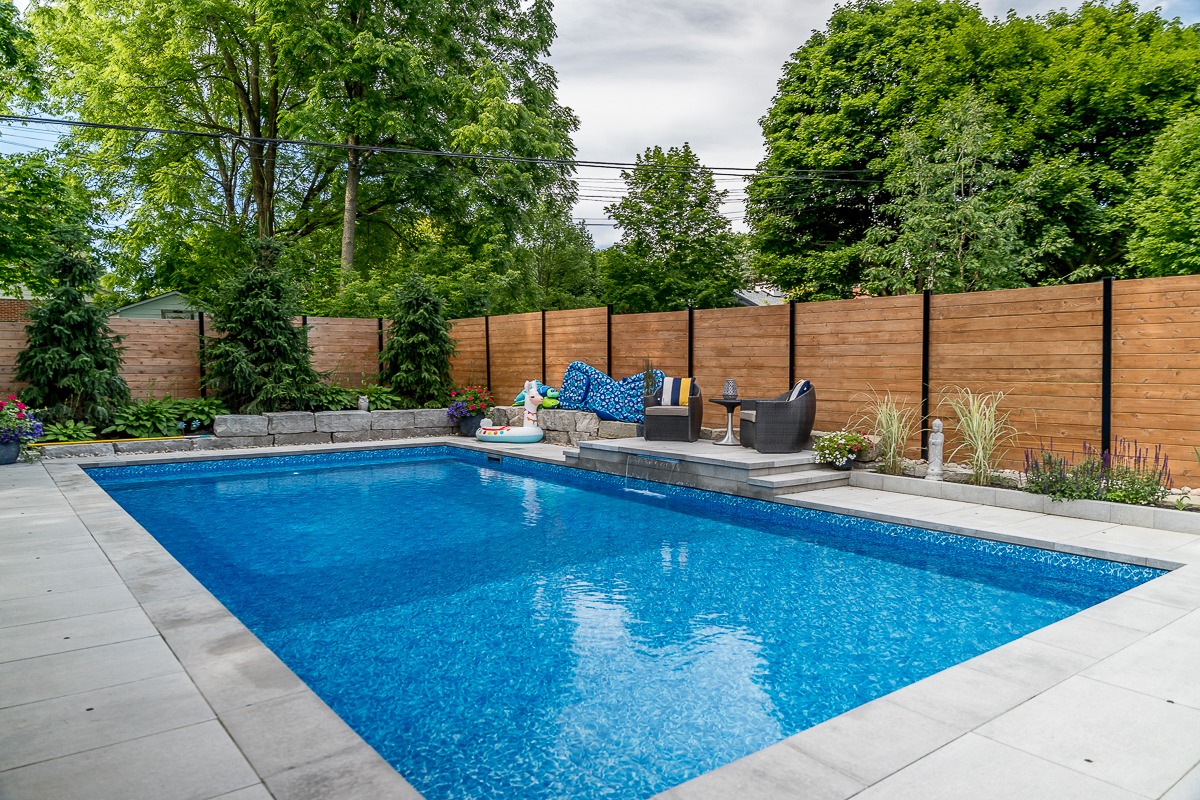 Backyard swimming pool with patio chairs.