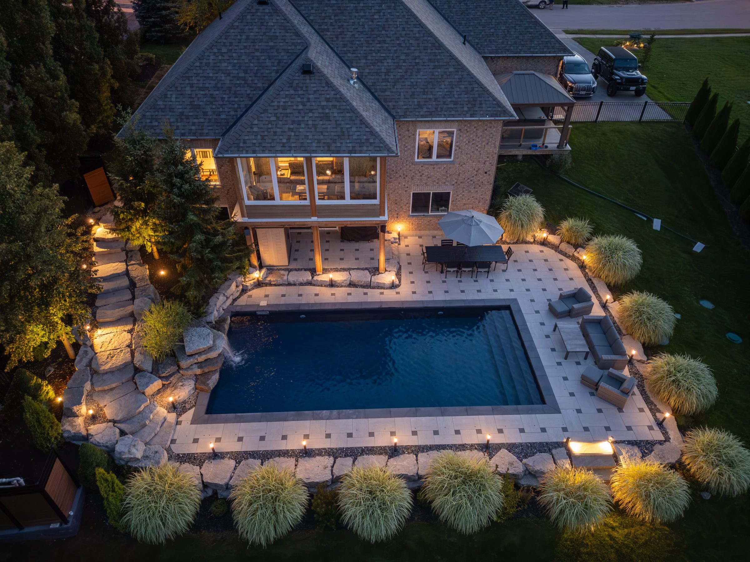 Aerial view of illuminated backyard with pool and patio.