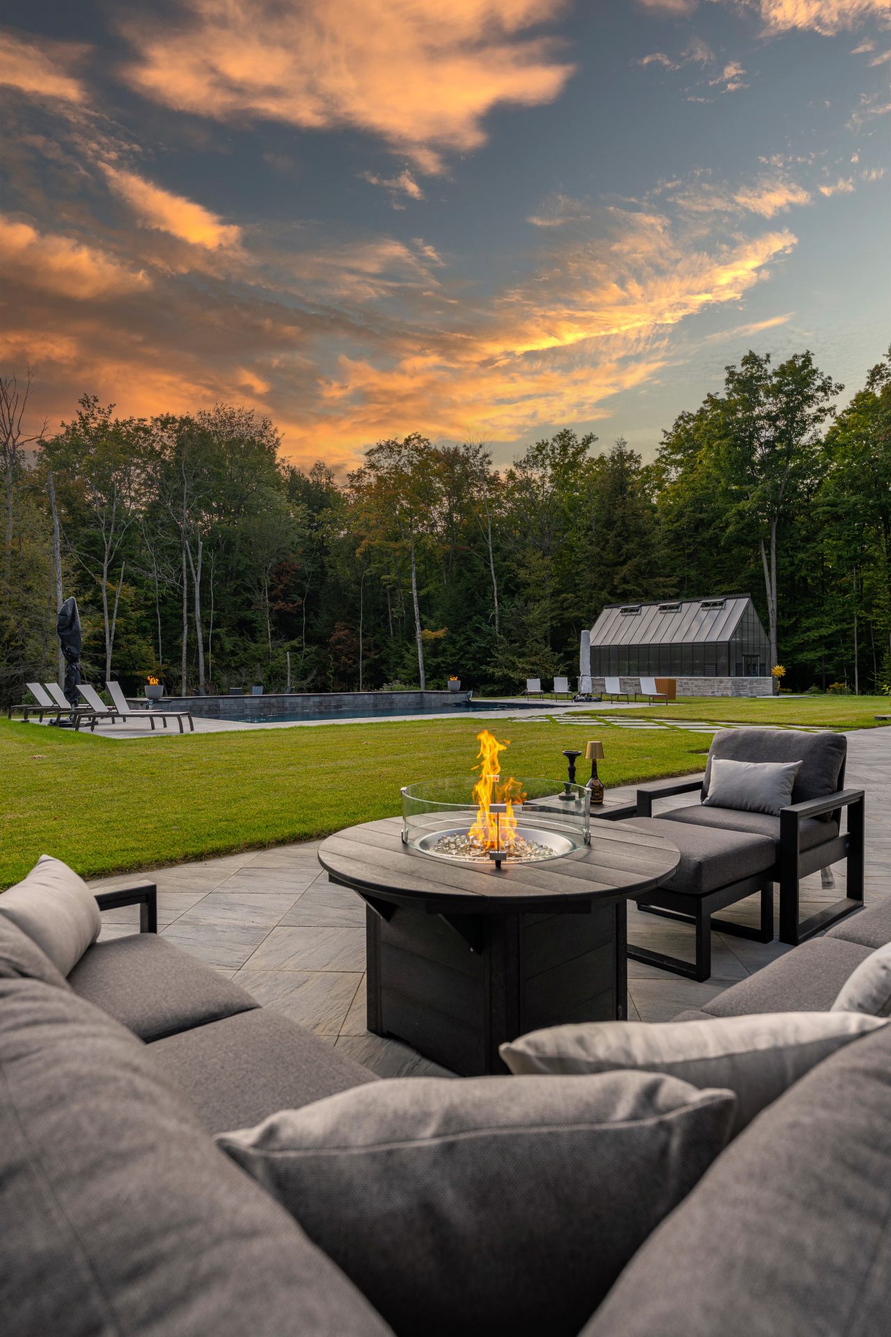 Outdoor patio with firepit, pool, and sunset view.