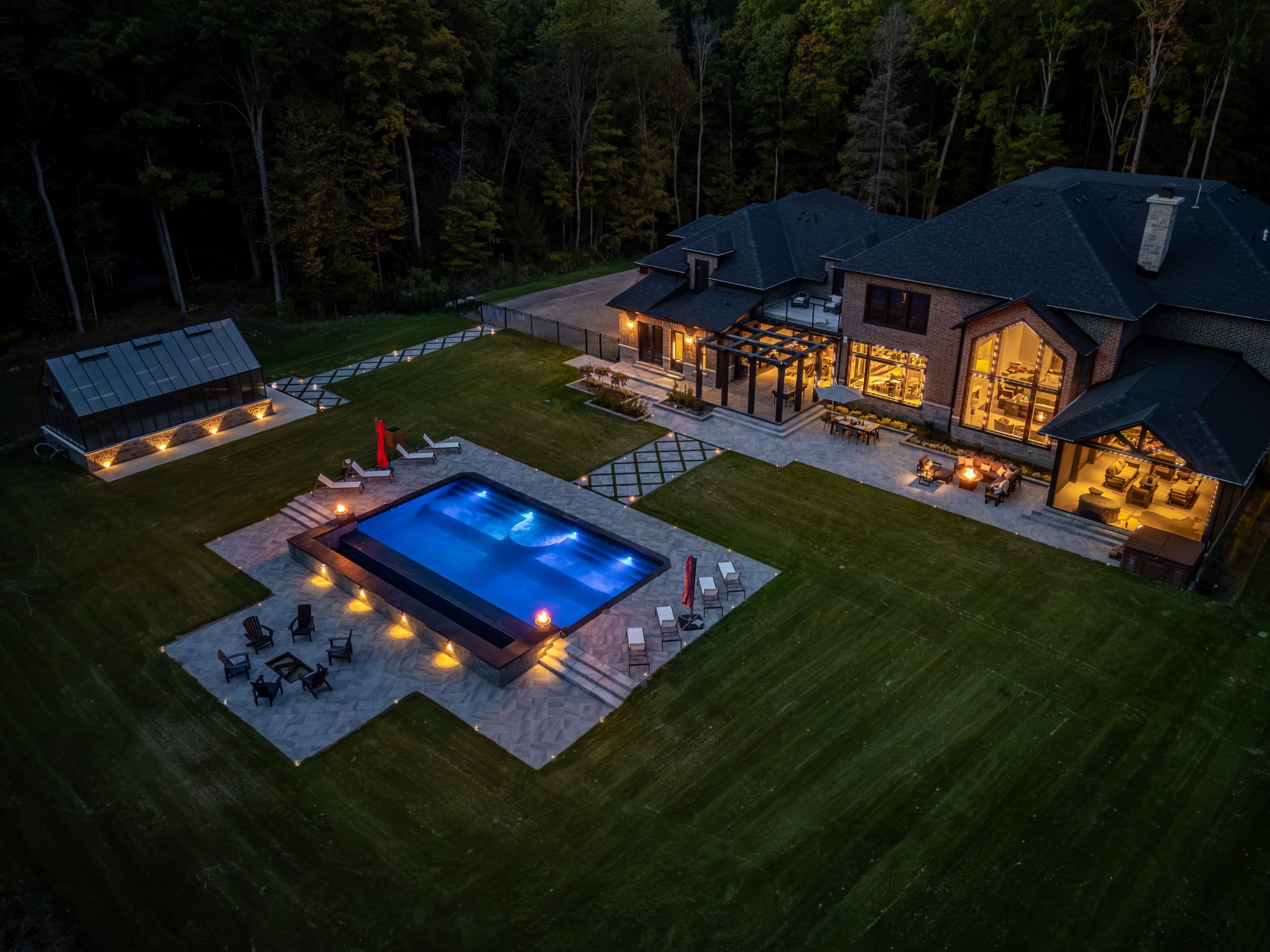 Luxury home with illuminated pool and garden at night.