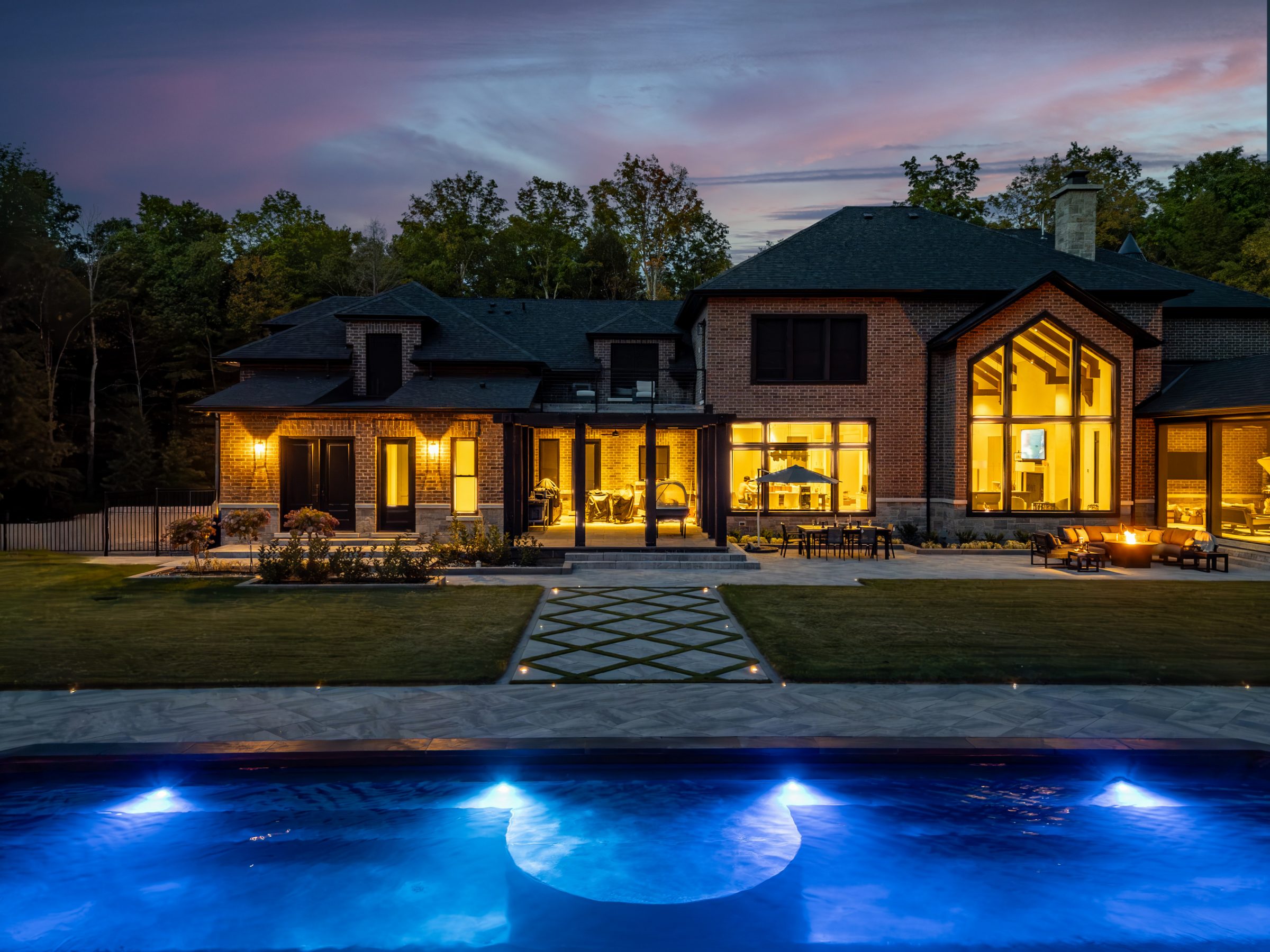 Luxury house with illuminated pool at dusk.