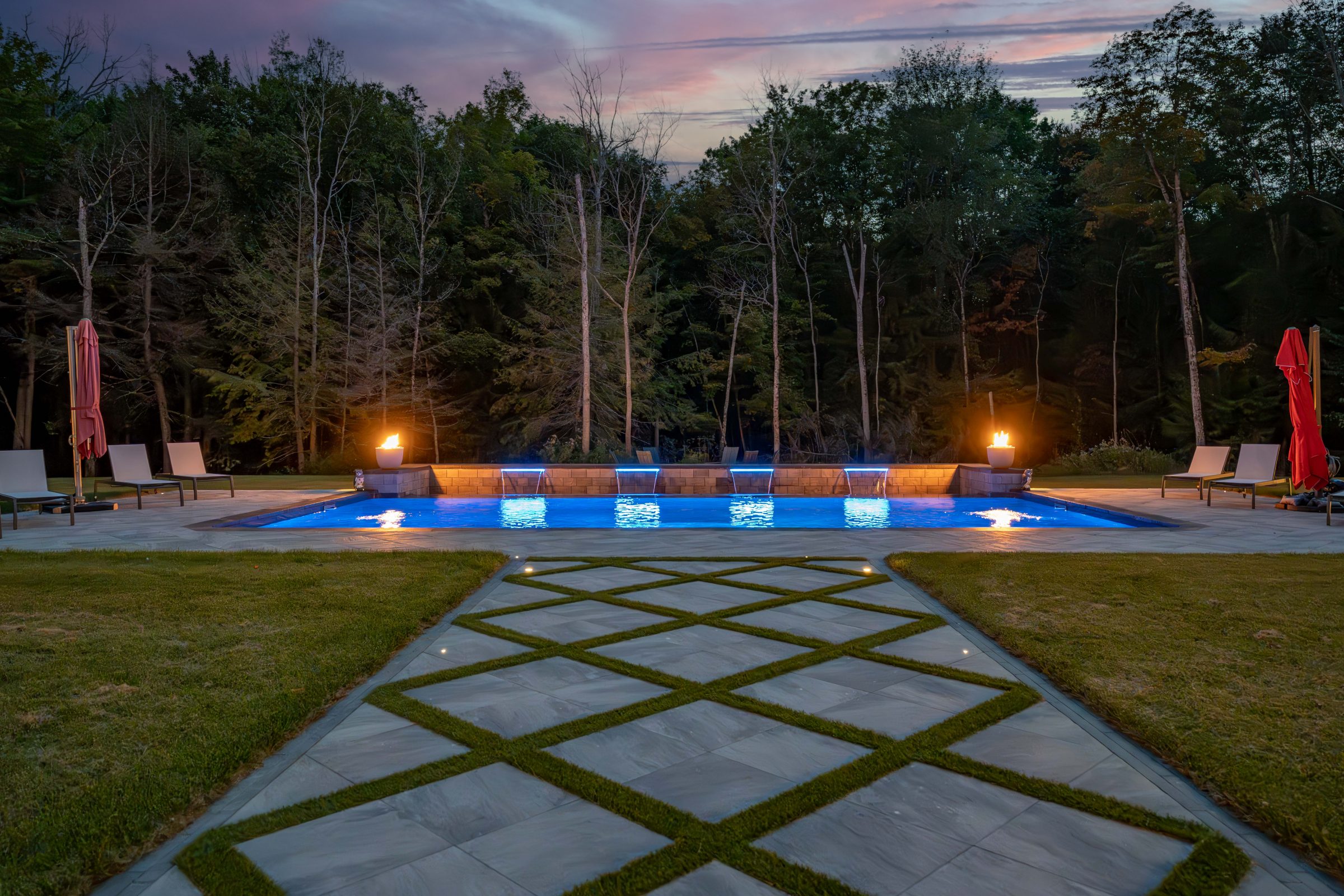 Evening poolside with fire features and lights.