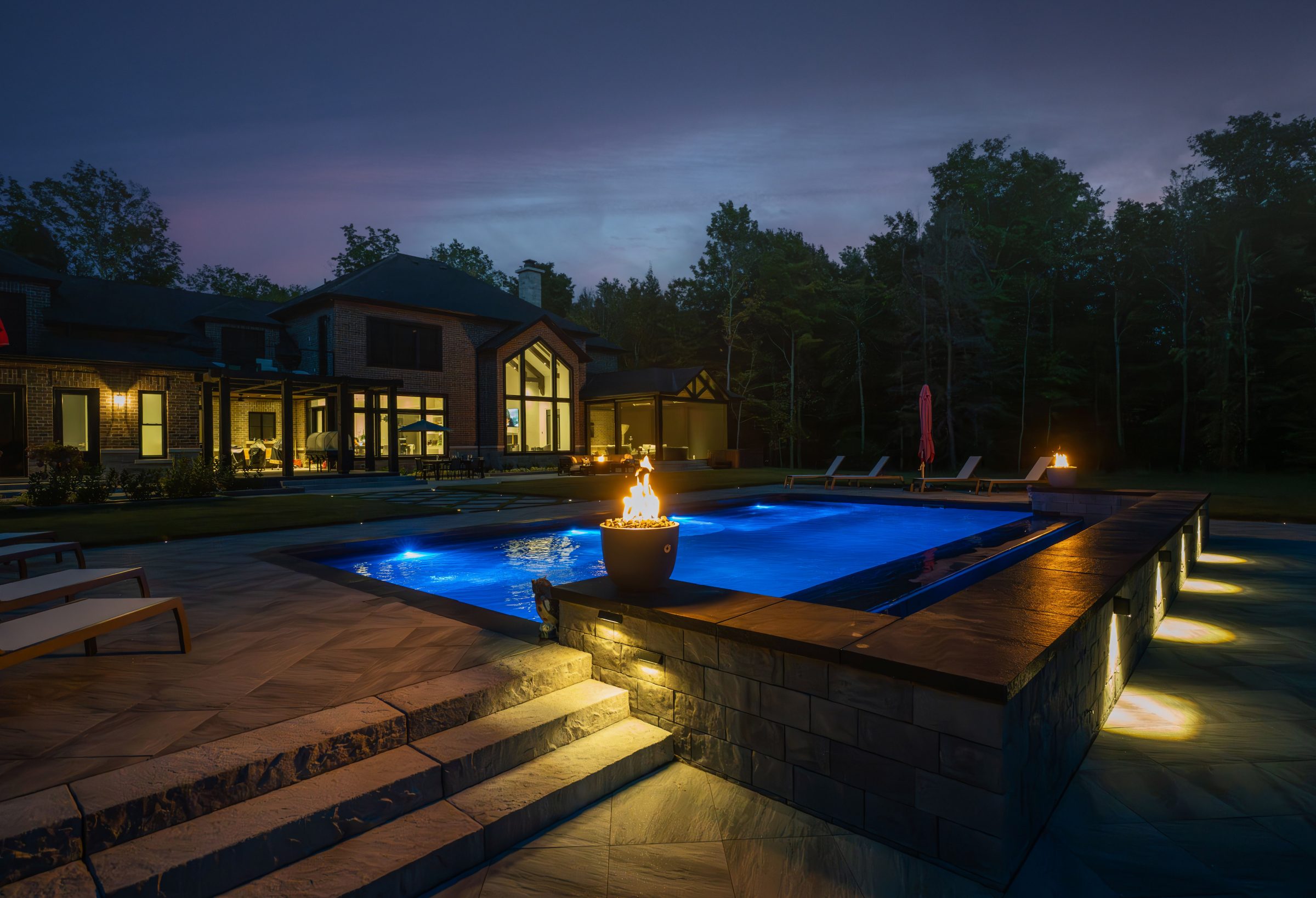 Luxury home with illuminated pool at night