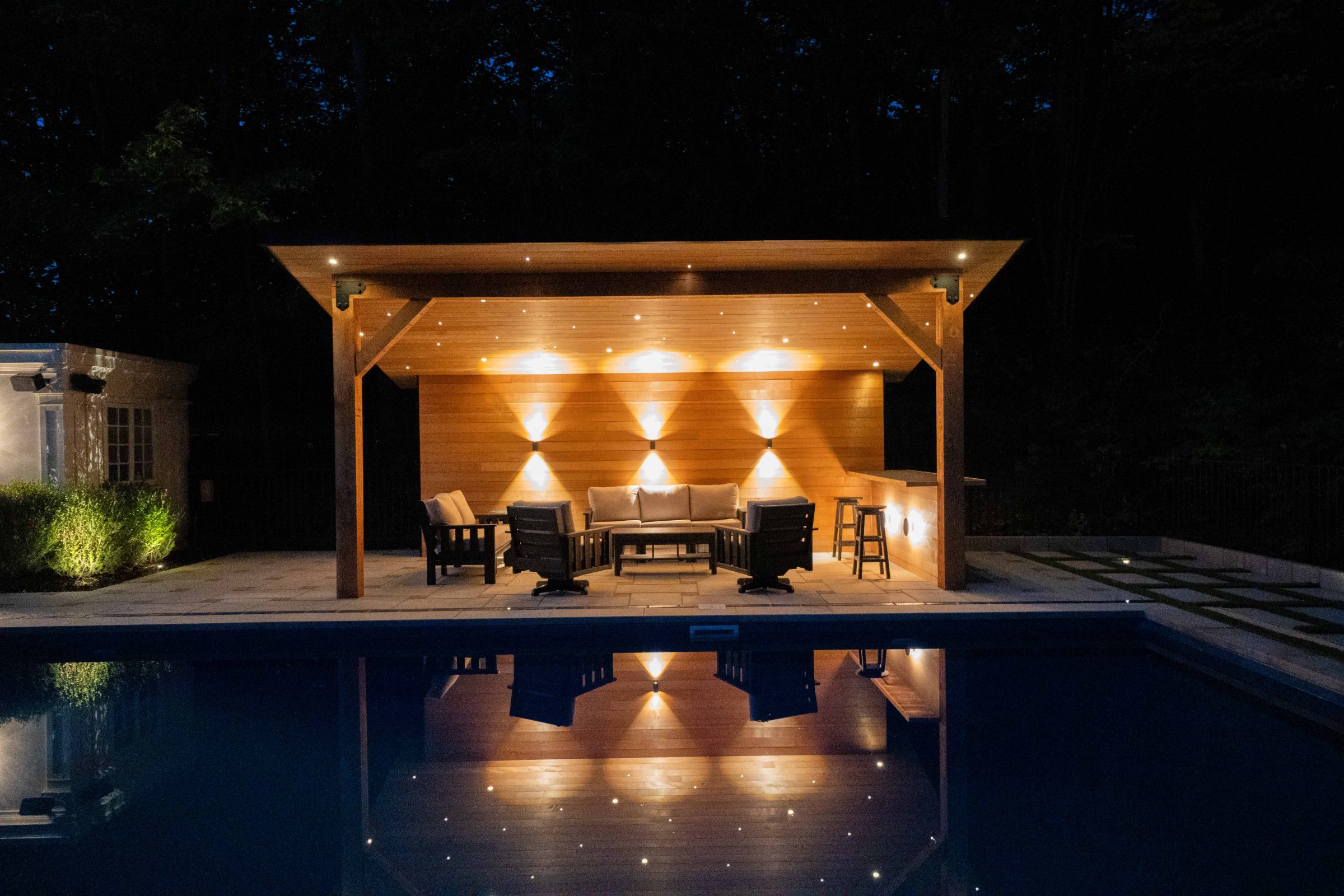 Outdoor seating area with evening lighting by pool.