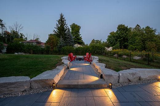 Backyard patio with red chairs and evening lighting.