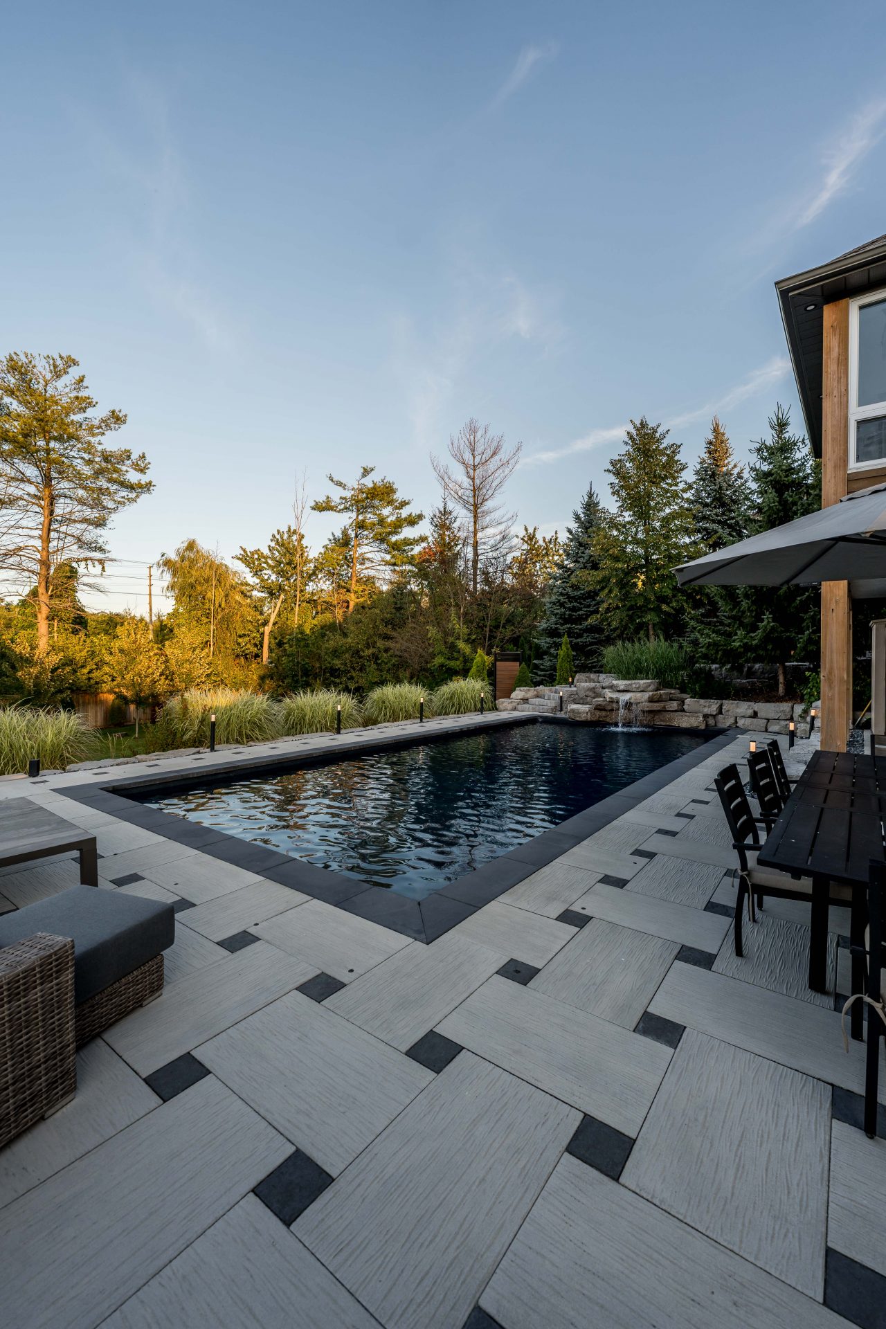 Modern backyard pool with patio and trees