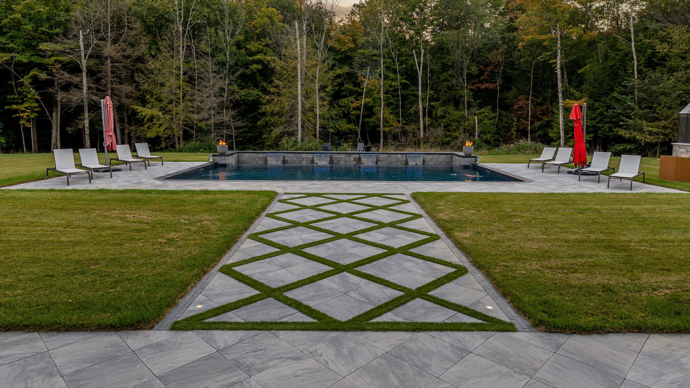 Luxury outdoor pool with lounge chairs and trees.