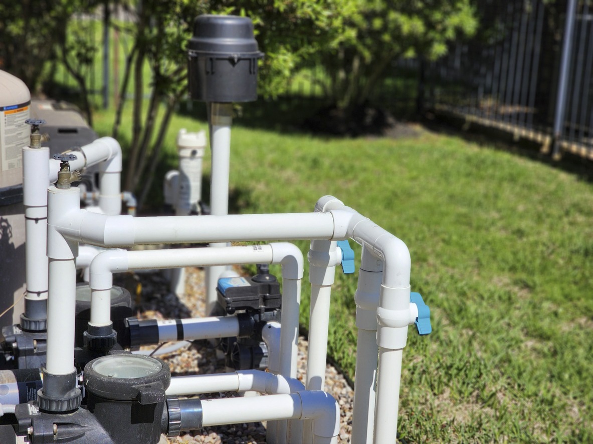 Pool pump system with PVC pipes outdoors.