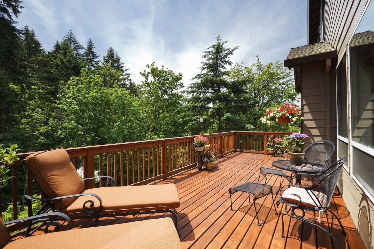 Wooden deck with chairs and forest view.