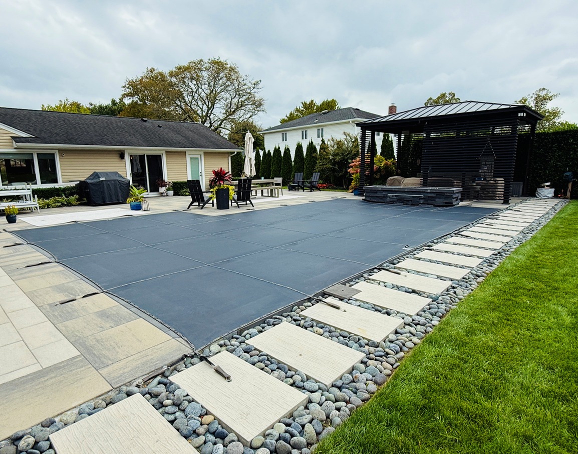 Backyard with pool cover and patio.