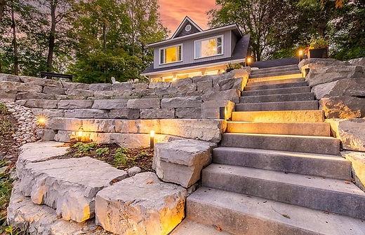 Lit stone path leading to a house at dusk.
