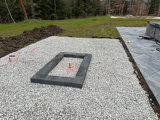 Gray stone fire pit construction on gravel patio