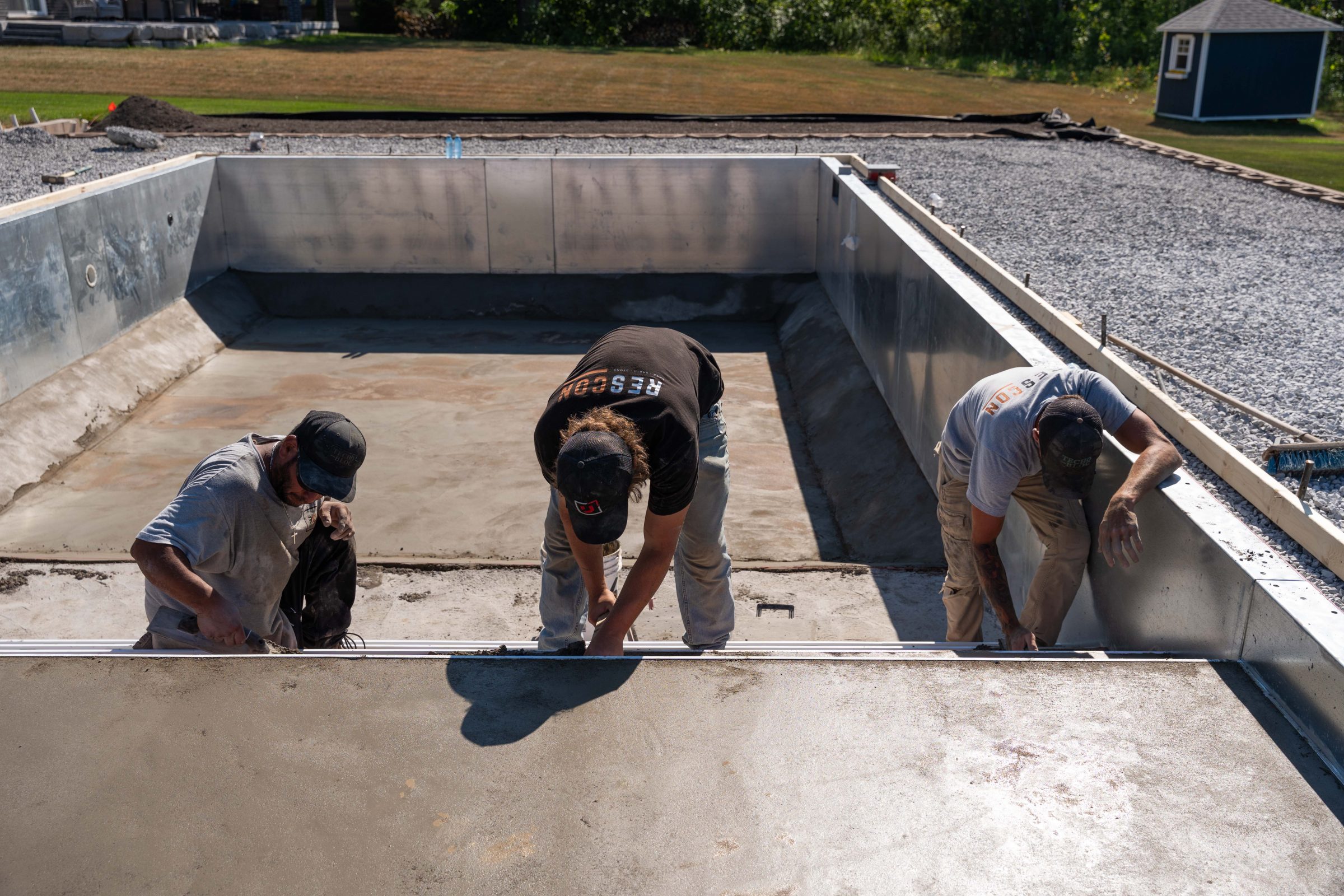 Construction workers building a concrete swimming pool.