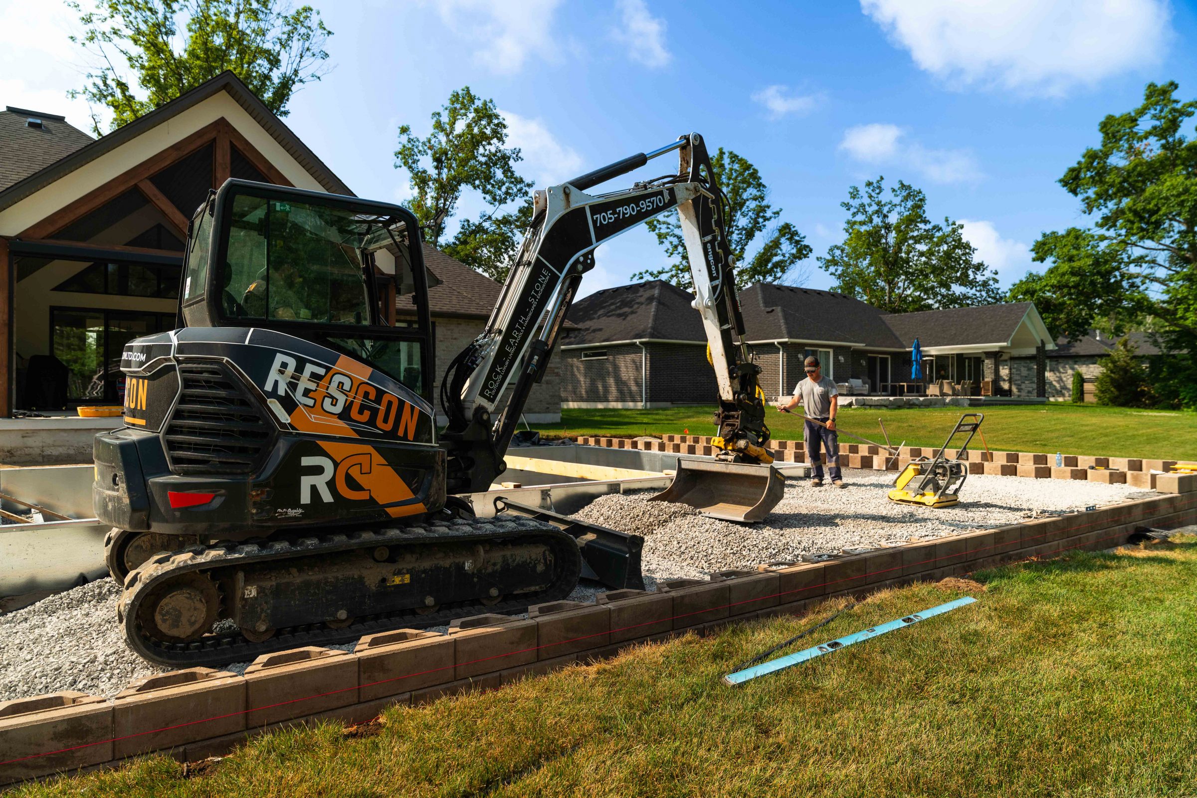 Construction worker with excavator building a backyard patio.