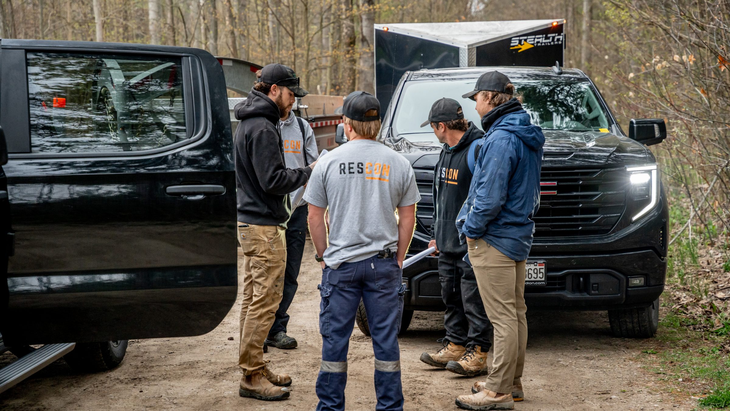 Group of workers discussing by parked trucks.
